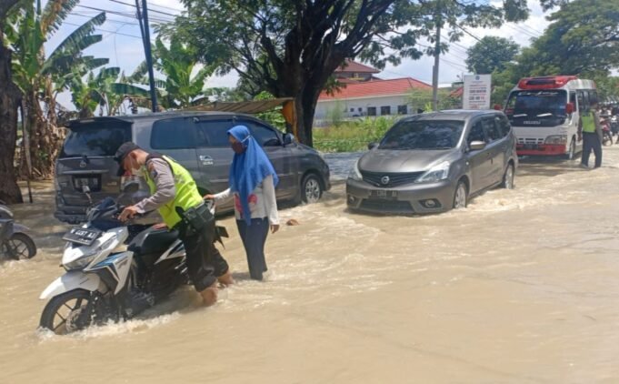 Jalan Tergenang Banjir, Polsek Benjeng Dan Koramil Bantu Dorong Motor yang Mogok